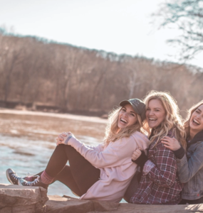 Group of smiling girls sitting by a river